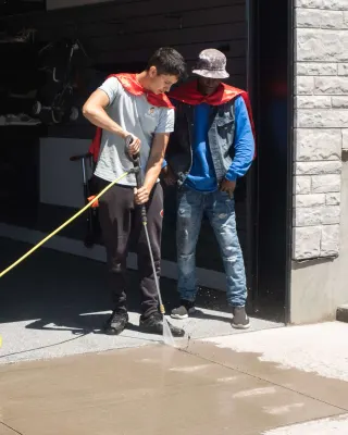 Two crew members pressure washing a driveway in Kitchener-Waterloo