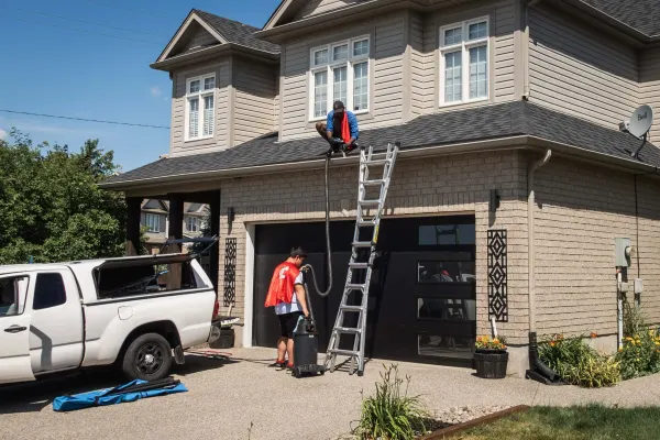 Hero Washing crew cleaning the gutters of a Kitchener-Waterloo home from a ladder