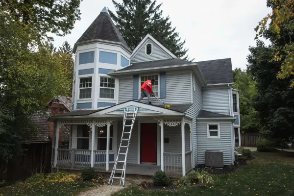 Crew member cleaning the roof of a two-storey house in Kitchener-Waterloo