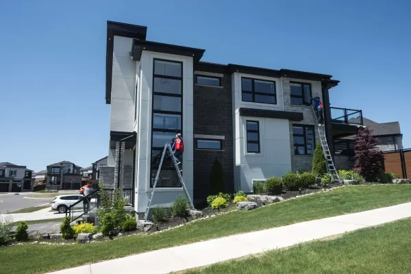 Crew on ladders cleaning the windows of a modern house in Kitchener-Waterloo